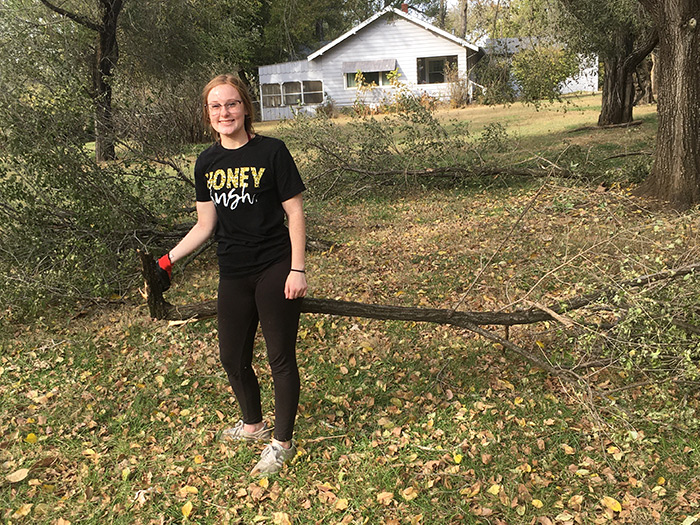 aces student volunteer clearing a yard of broken branches