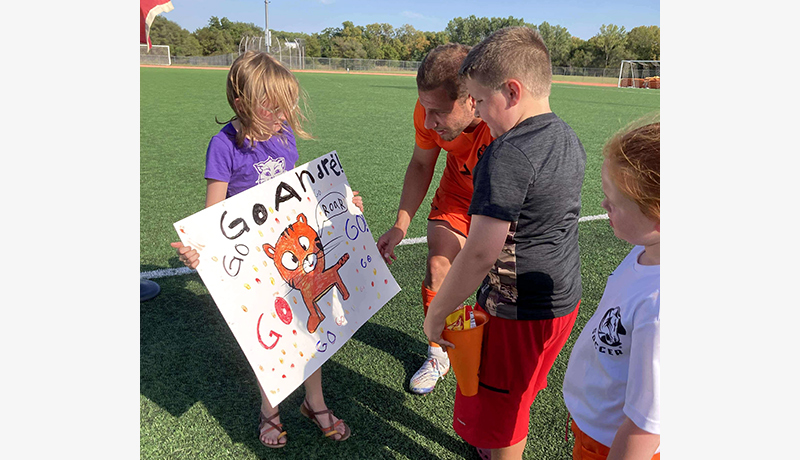 child showing a poster to a soccer player