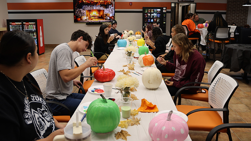 students painting pumpkins at halloween party