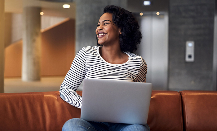 smiling woman using a laptop on a lobby couch
