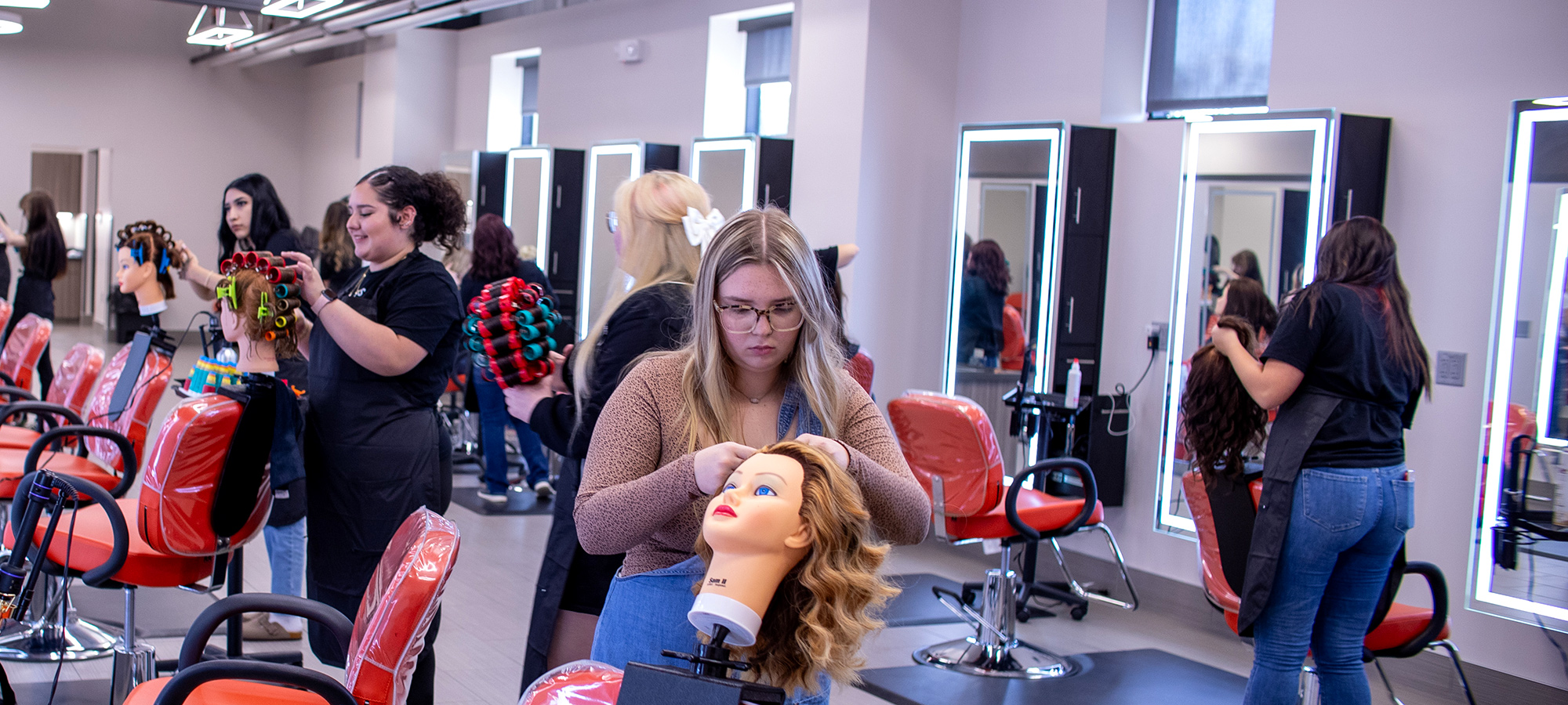 student curling hair on a mannequin