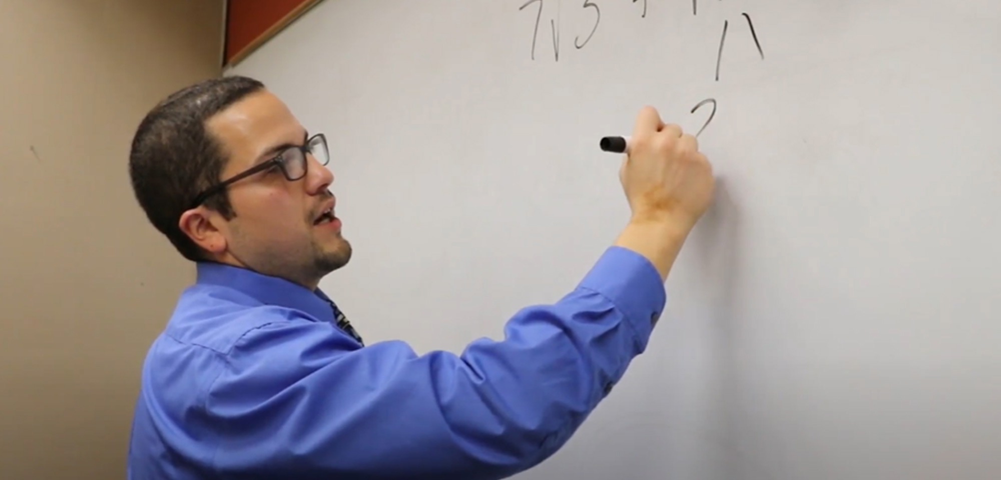 math instructor writing an equation on the white board