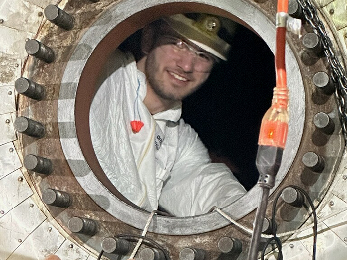Cowley NDT student pictured inside an entrance to a heat exchanger dressed in radiation protection equipment