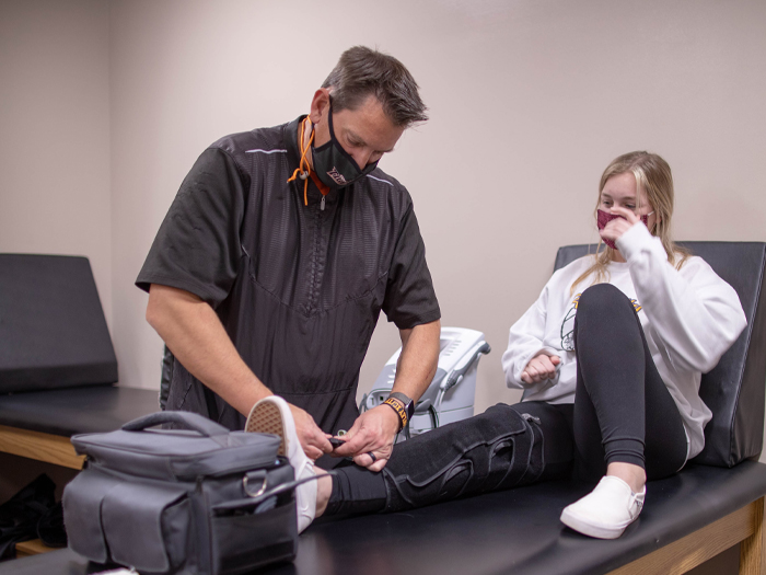 athletic trainer applying a brace to a student athlete