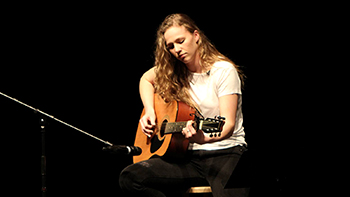 hannah nicolaisen singing and playing guitar at a concert